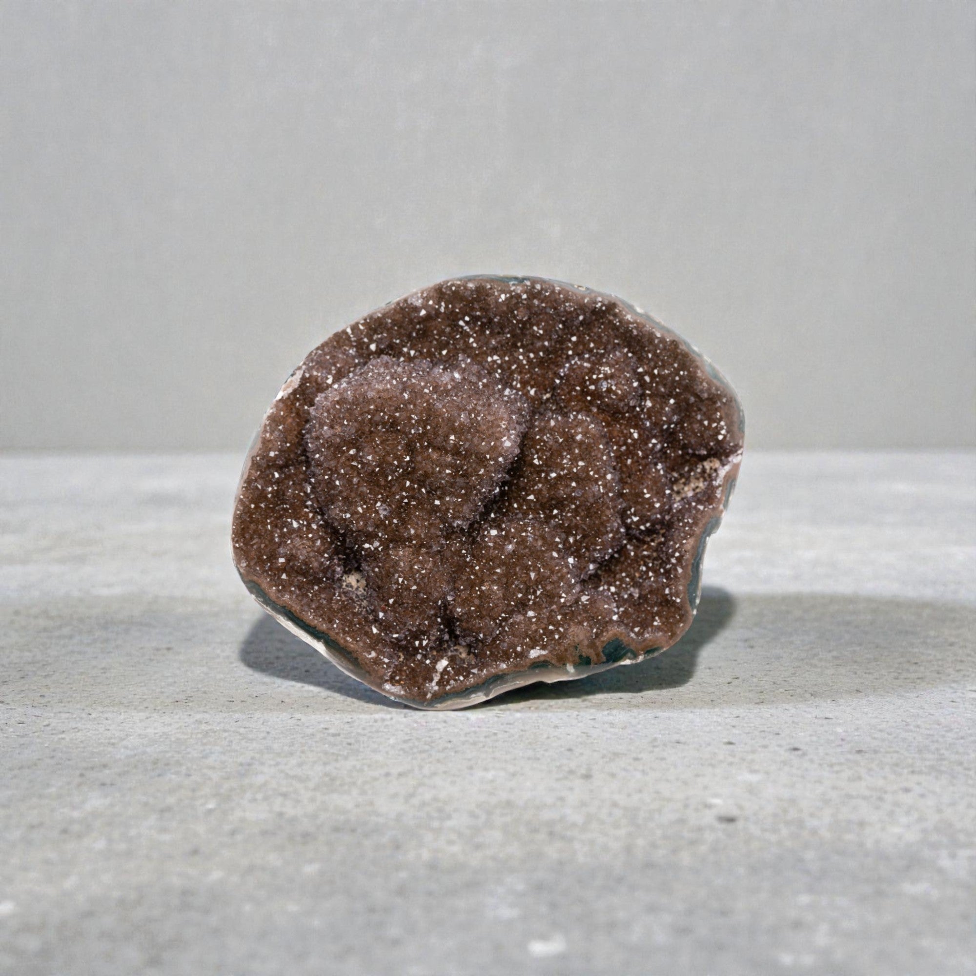 Small natural crystal geode featuring a sparkling reddish brown druzy quartz interior, layered agate banding, and organic volcanic formation in a compact decorative piece.
