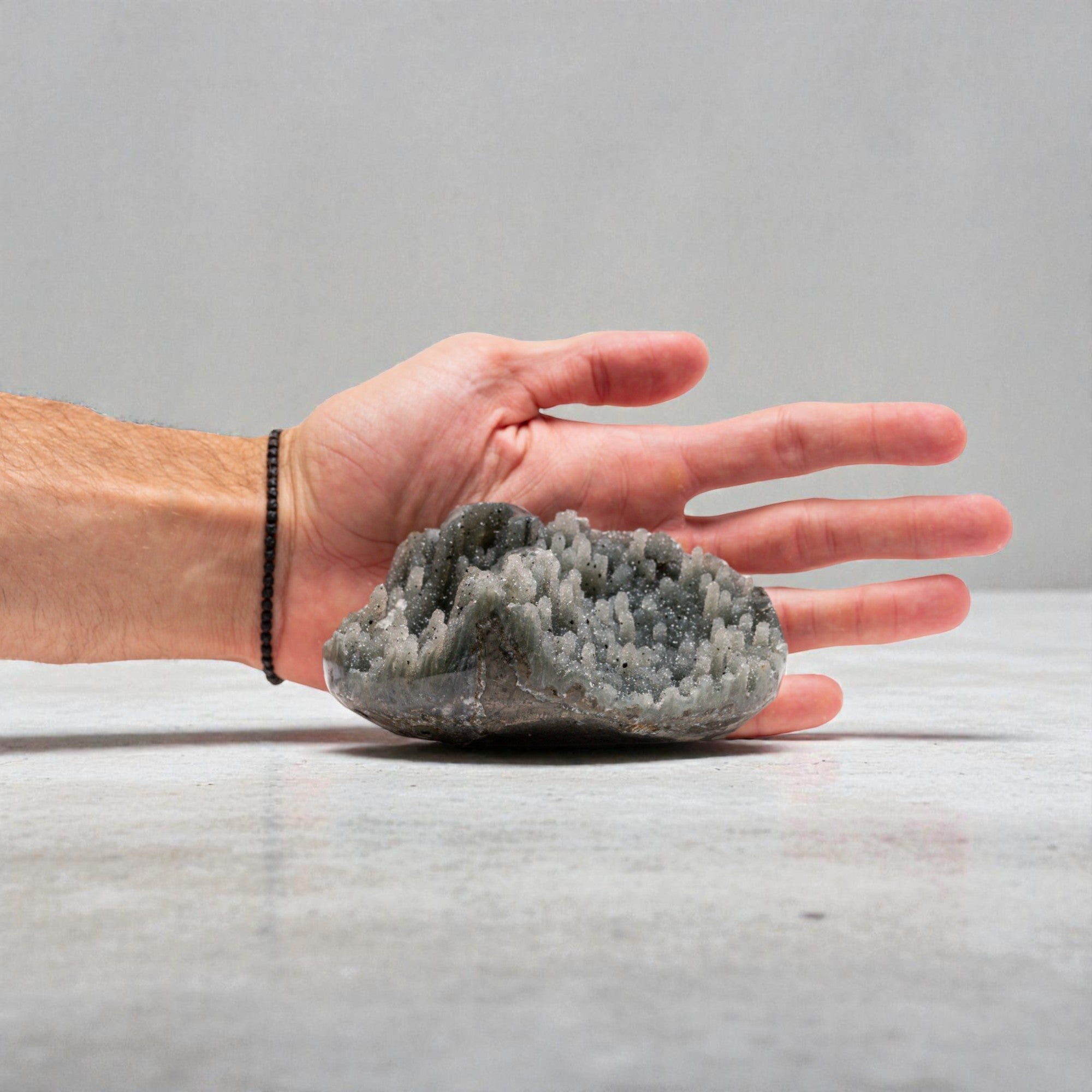 Mini druzy quartz geode with pale grey crystal points rising from a chalcedony base, featuring a sparkling druzy quartz interior and natural volcanic layering in a sculptural, hand-sized formation.