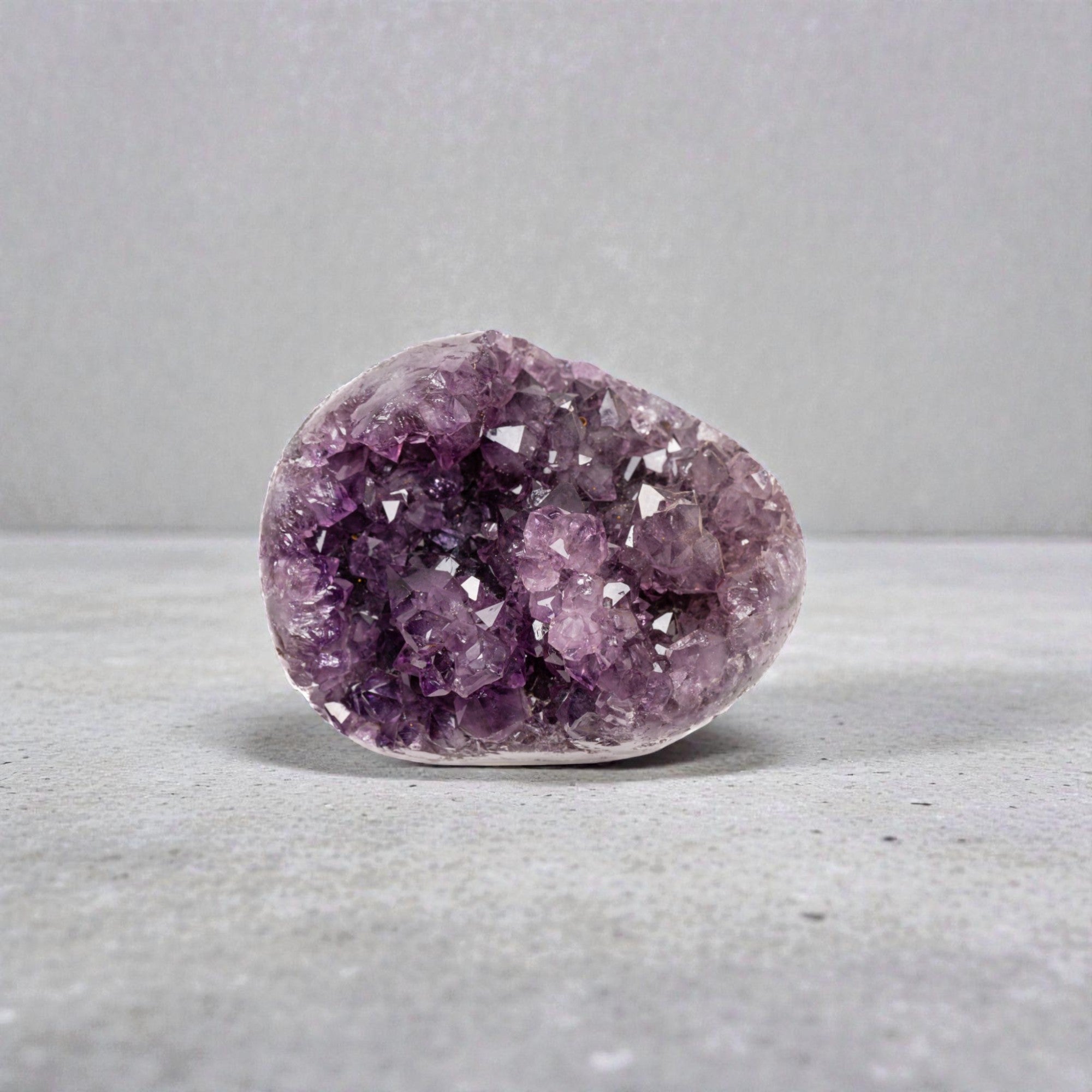 Mini amethyst geode with sparkling purple quartz crystals, visible agate banding, and a polished base in a compact sculptural form.