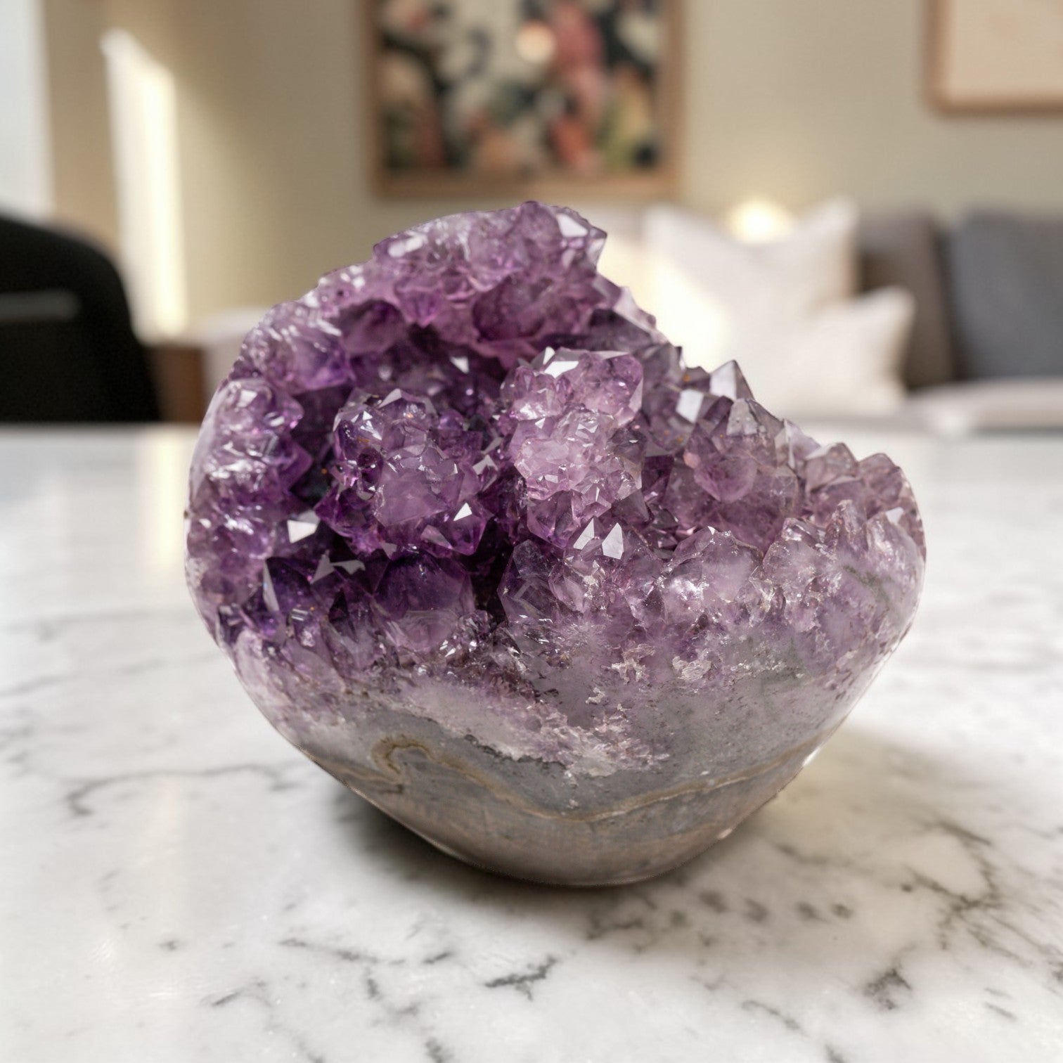 Hand-sized purple amethyst crystal geode showcasing deep violet points and organic mineral banding in a refined display piece.