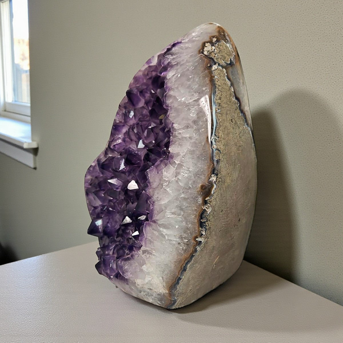 Uruguayan amethyst geode showing purple druzy crystals and multitone agate stripes along the exterior.