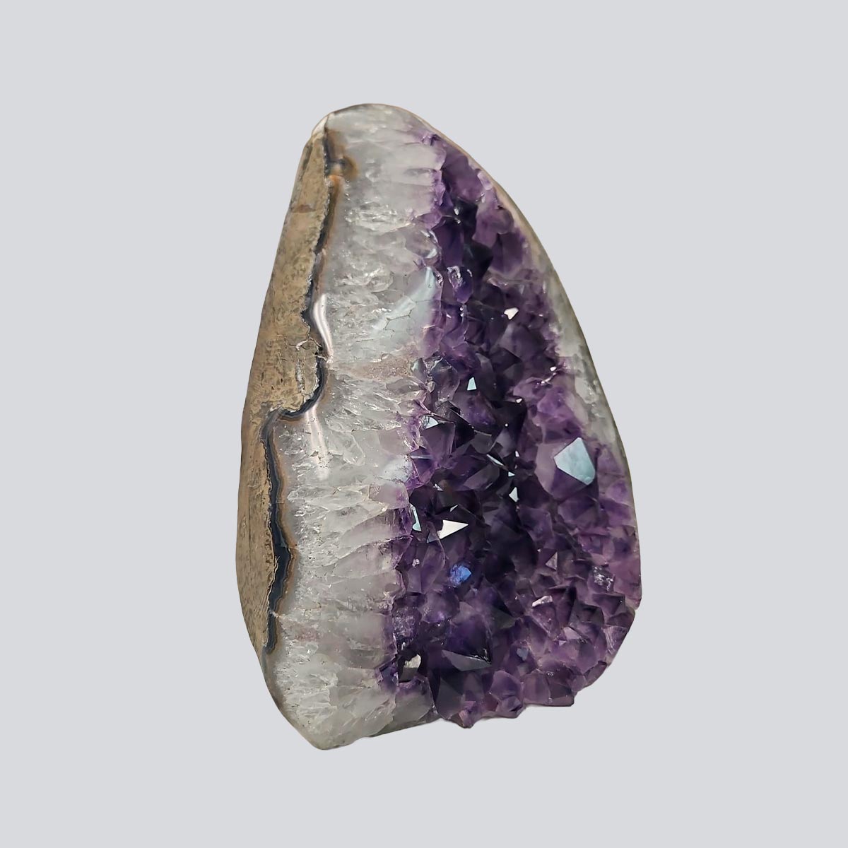 Side view of an amethyst rock with violet crystal cavity, white quartz banding, and natural agate layers.