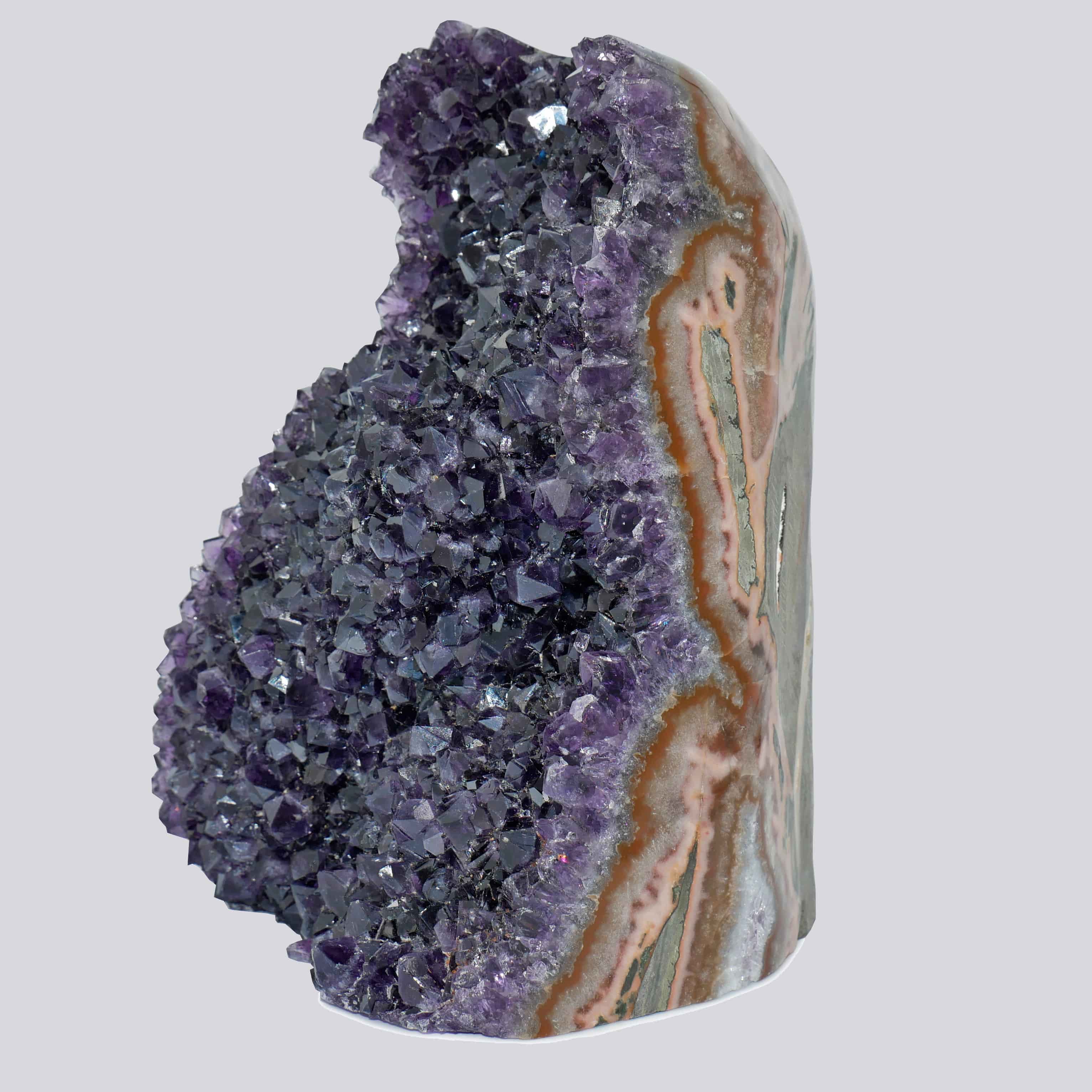 Side view of a tall Uruguayan amethyst geode with deep purple crystals and thick peach-grey agate banding.