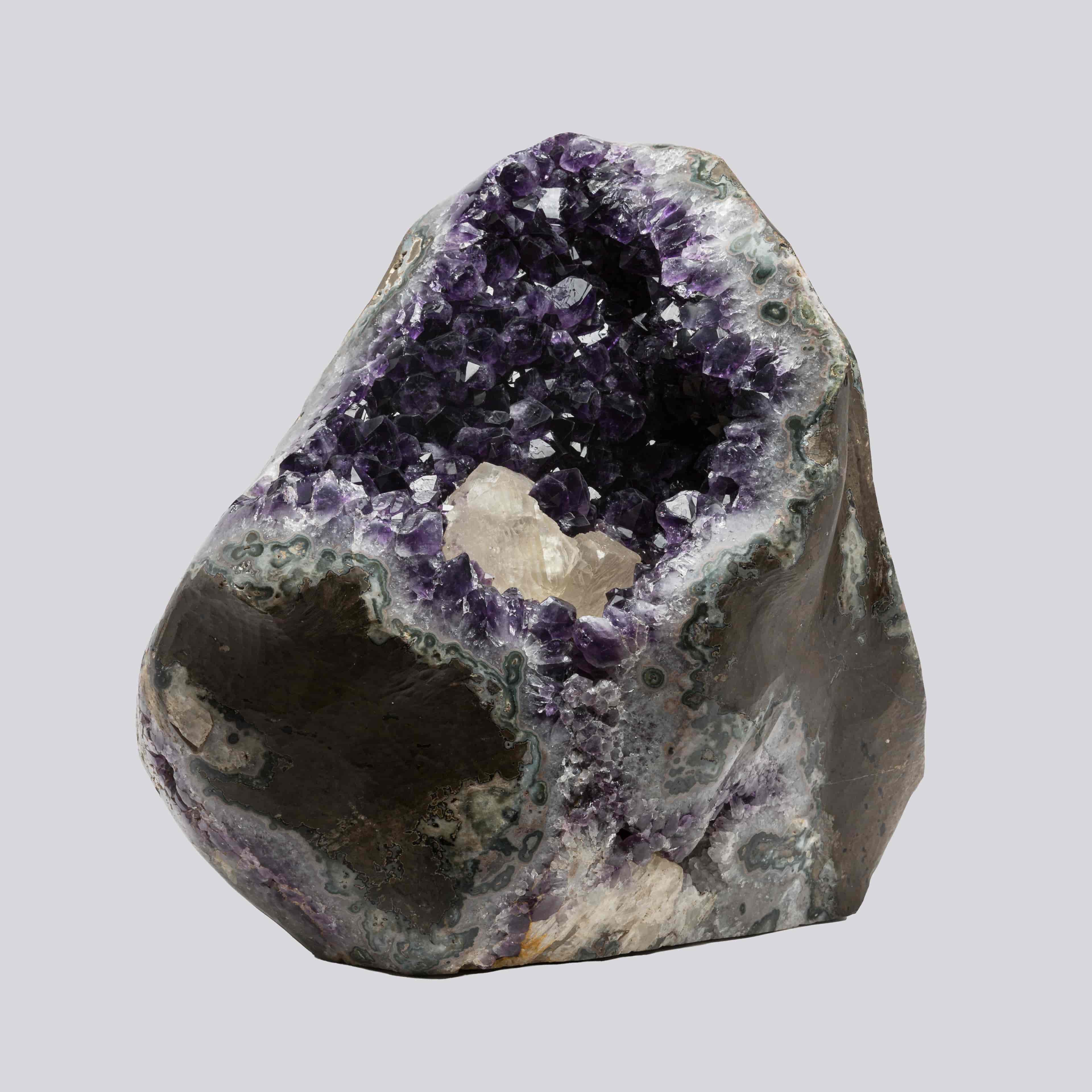 Asymmetrical amethyst geode from Uruguay featuring dark violet crystals, agate layers, and a bright white calcite core.