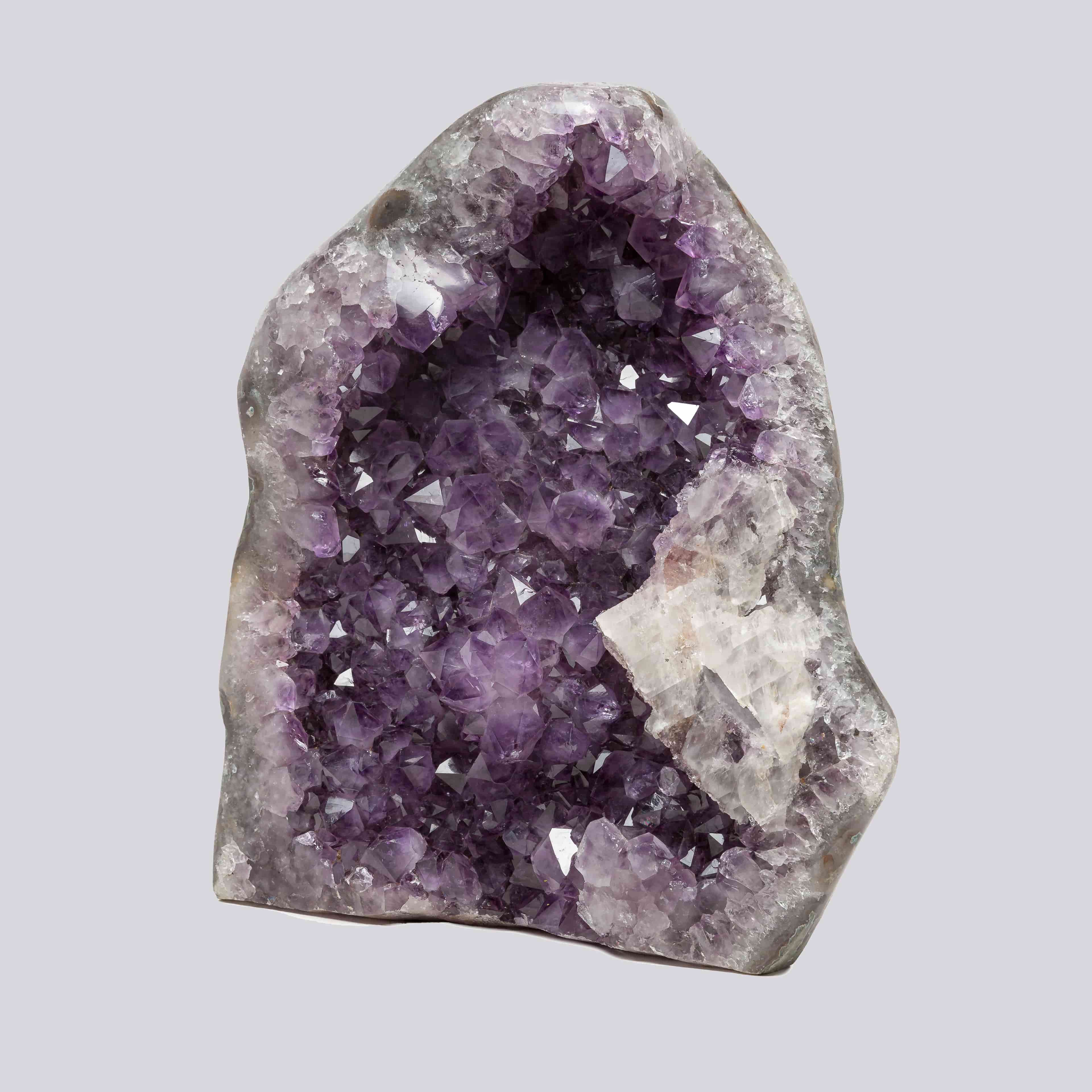 Deep purple Uruguayan amethyst geode with sparkling crystal points and a prominent white quartz formation on the right side.”