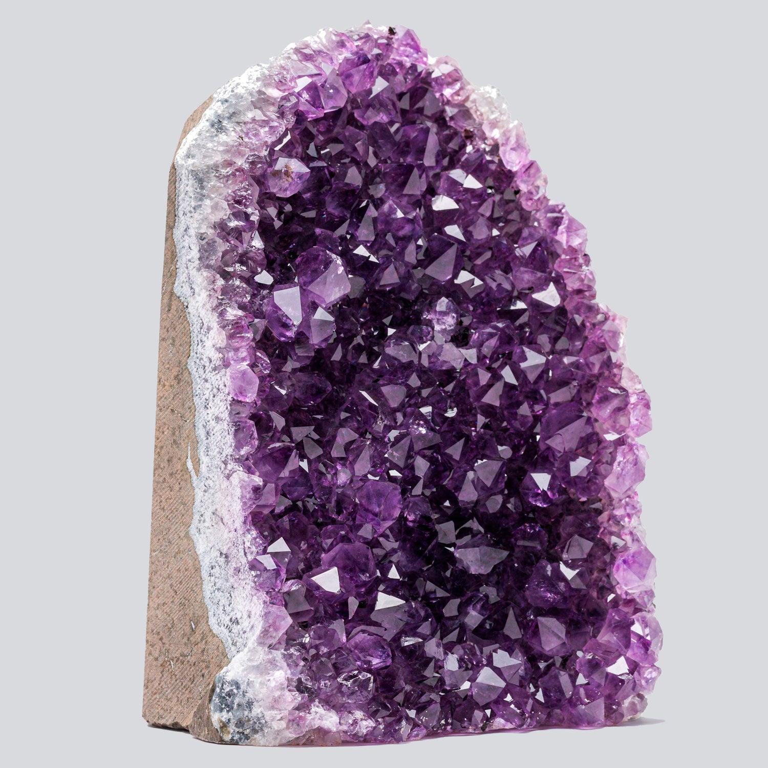 Deep purple Uruguayan amethyst geode with a cut base and vibrant crystal points, bordered by white quartz.