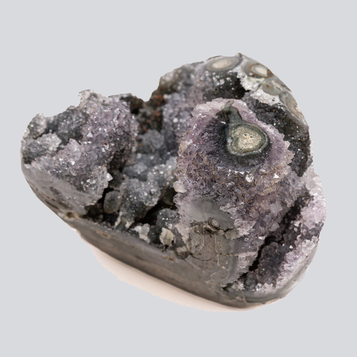 Small grey and lavender amethyst formation with druzy crystal clusters and banded agate eyes on the surface.