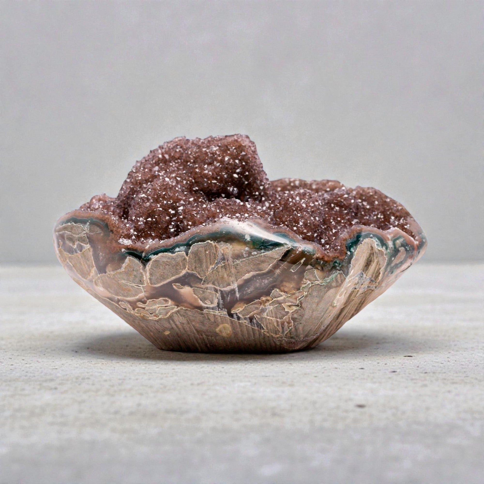 Mini druzy quartz geode with reddish brown crystal interior, strong banded agate layers, and visible chalcedony base, forming a sculptural hand-sized natural mineral specimen.