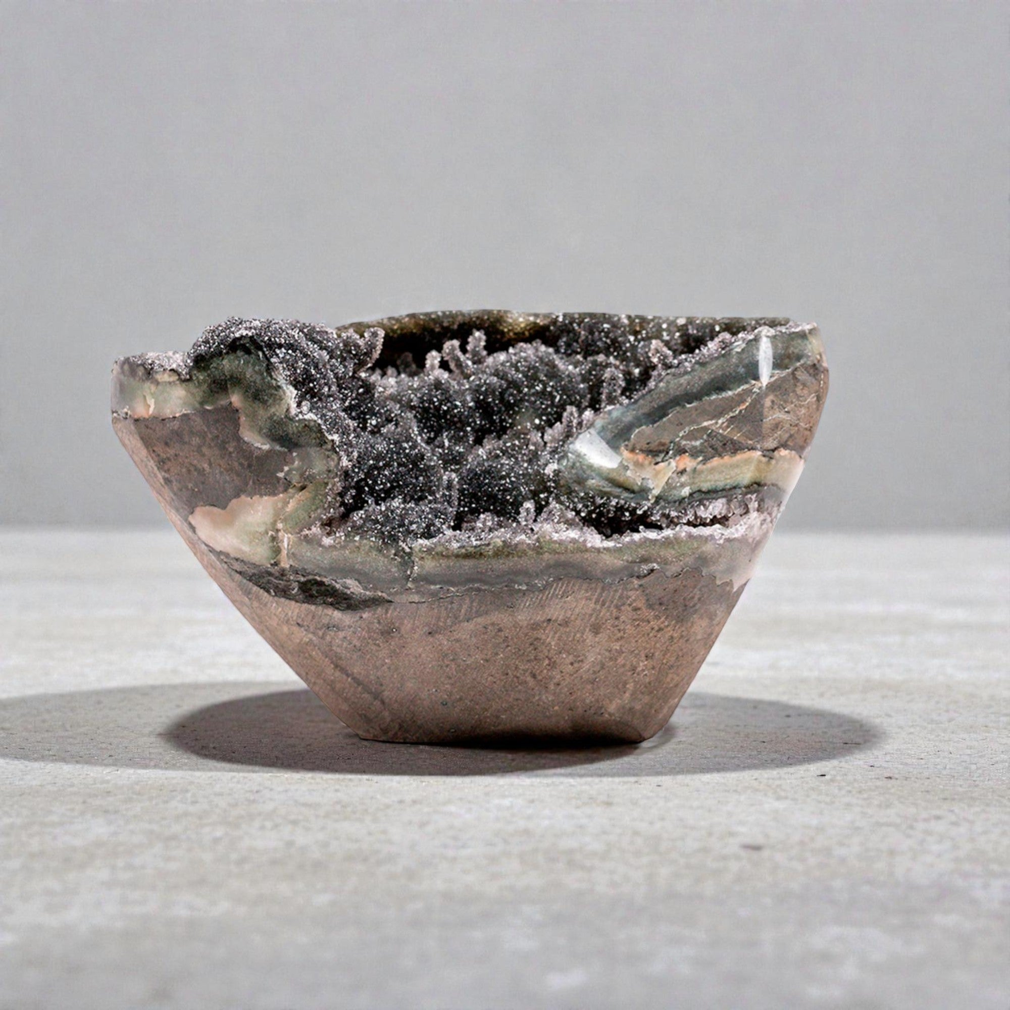 Hand-sized druzy quartz geode with deep grey micro-crystal texture, visible chalcedony layers, and architectural silhouette suited for luxury neutral decor.