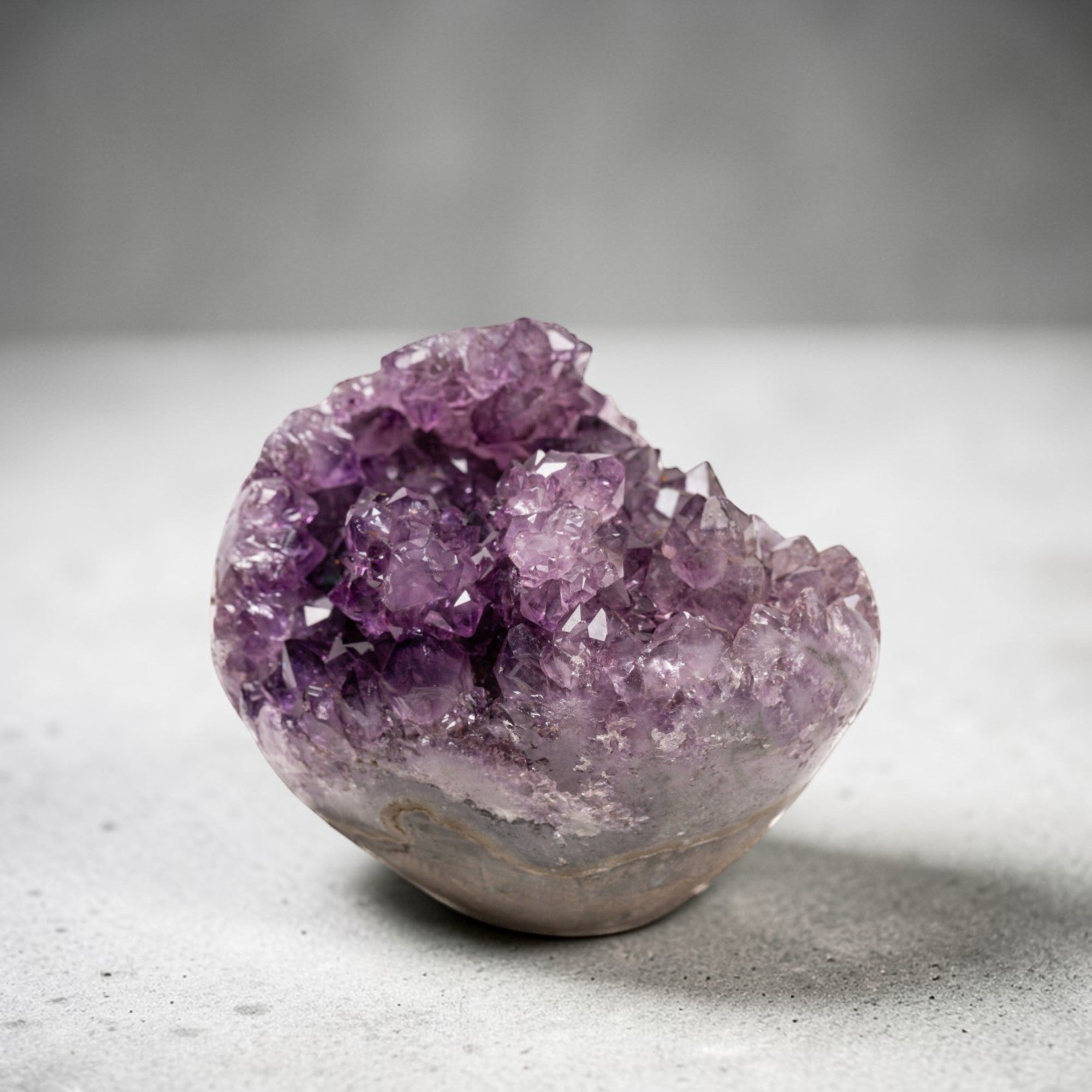 Small natural quartz geode featuring layered agate and a vibrant druzy amethyst interior formed within a volcanic cavity.