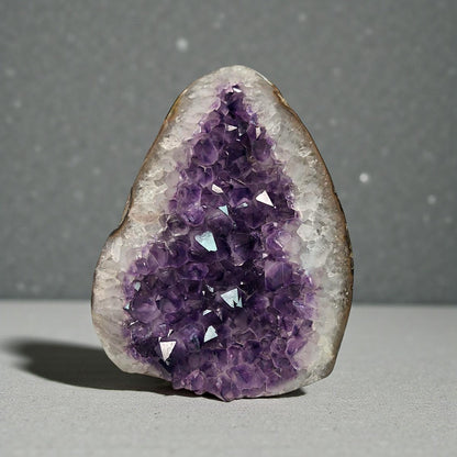 Triangular Uruguayan amethyst geode with deep purple crystal points and clear quartz edges.
