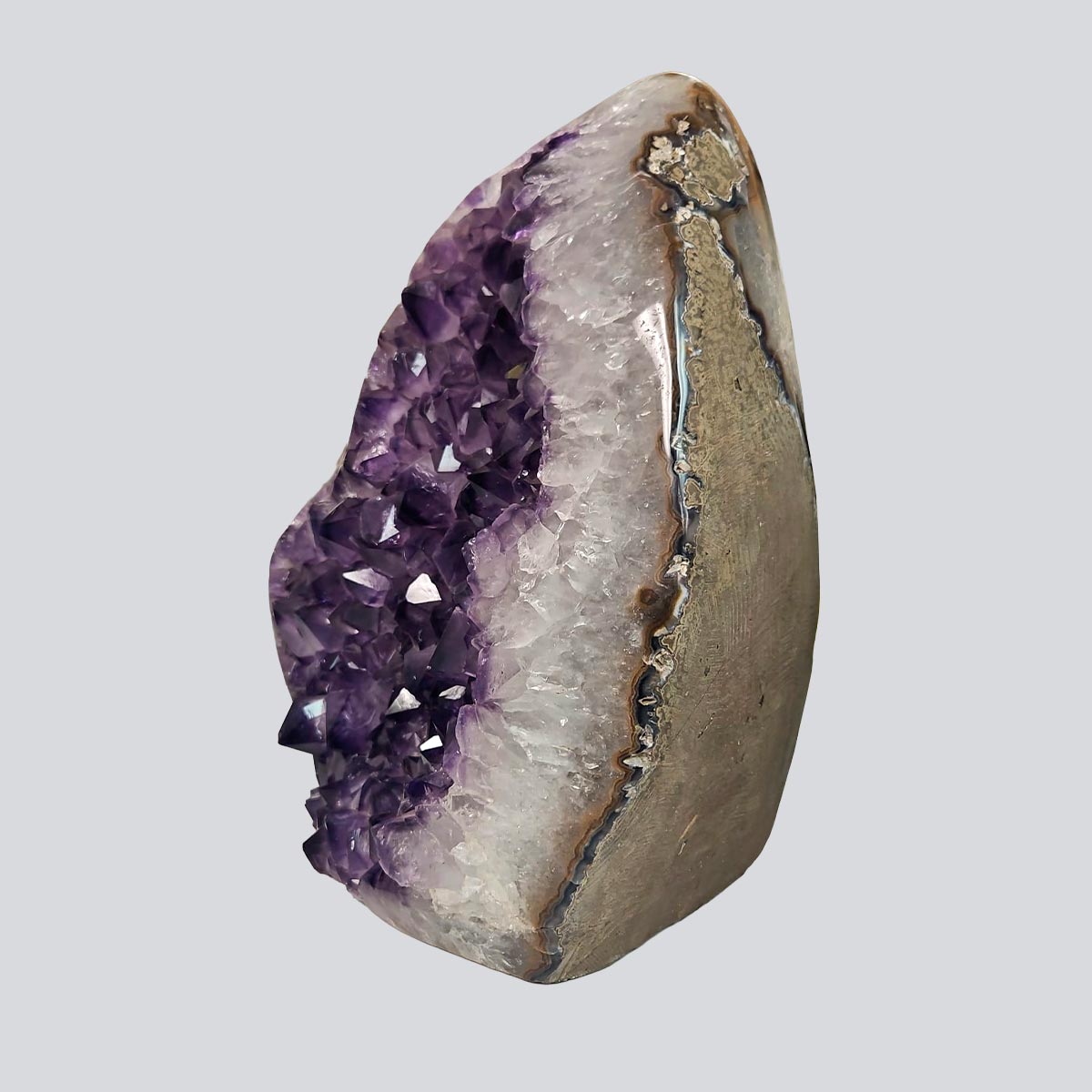 Side view of an amethyst rock with violet crystal cavity, white quartz banding, and natural agate layers.
