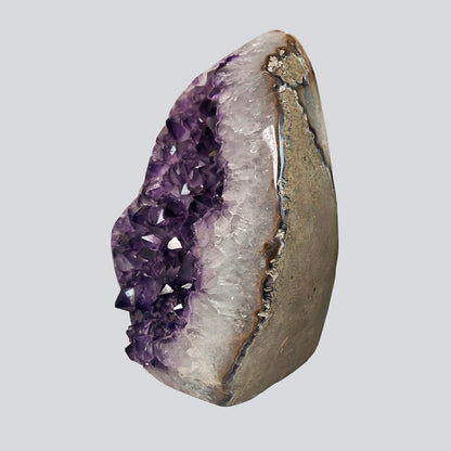 Side view of an amethyst rock with violet crystal cavity, white quartz banding, and natural agate layers.