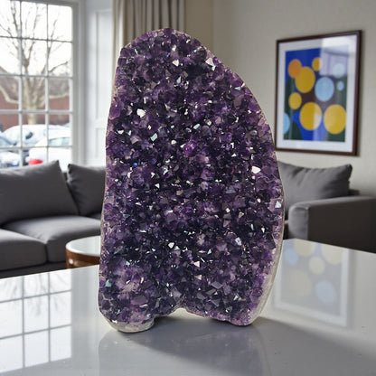 Upright amethyst cluster from Uruguay with rich purple crystals and strong light reflections highlighting its faceted surface.