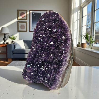 Upright amethyst cluster from Uruguay with rich purple crystals and strong light reflections highlighting its faceted surface.