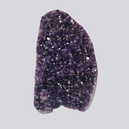 Huge deep violet Uruguayan amethyst cluster standing upright in natural light, featuring dense sparkling crystal points