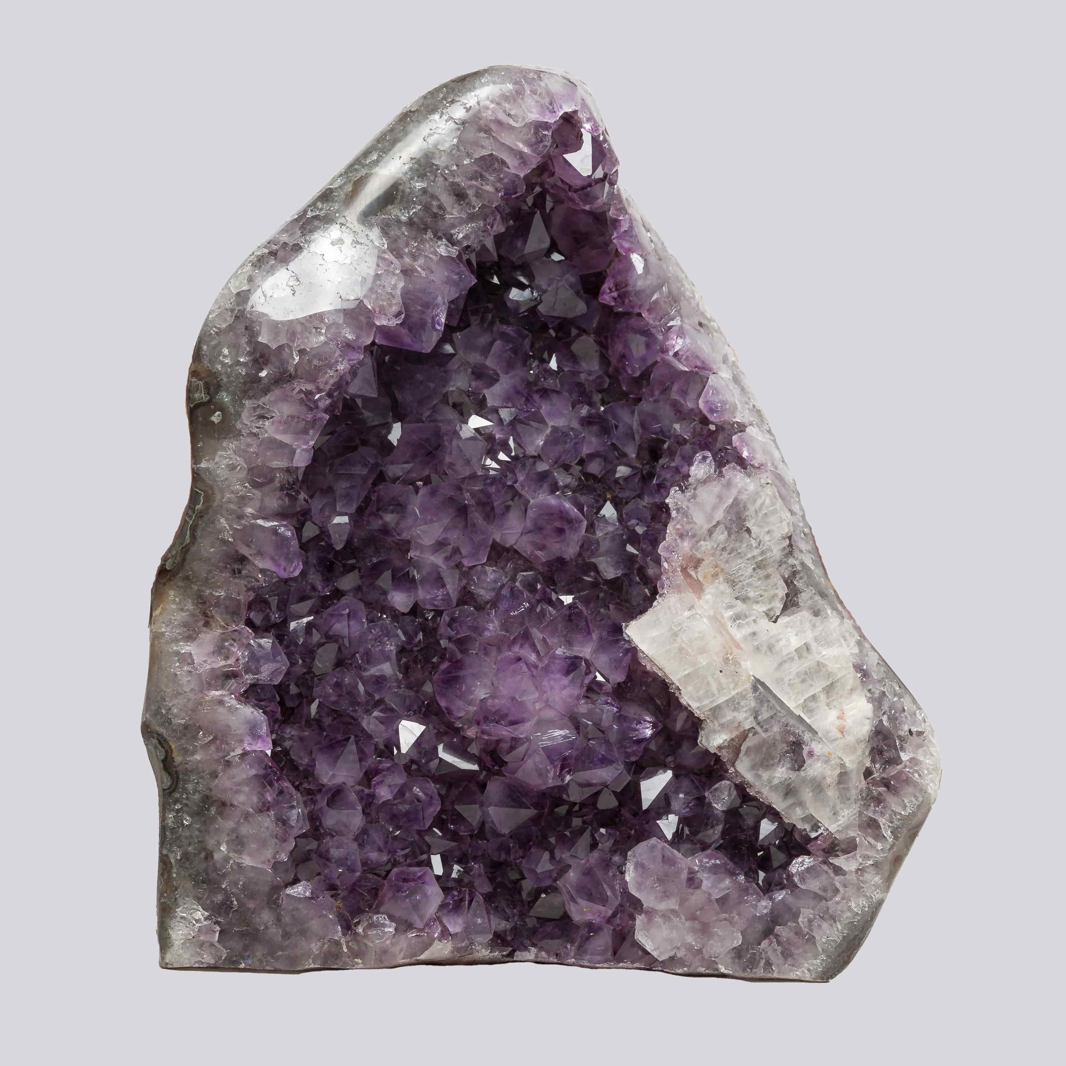 Deep purple Uruguayan amethyst geode with sparkling crystal points and a prominent white quartz formation on the right side.