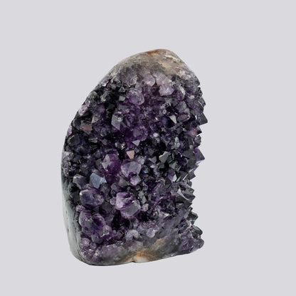Tall deep-purple Uruguayan amethyst geode with dense crystal points and a natural rounded matrix top.