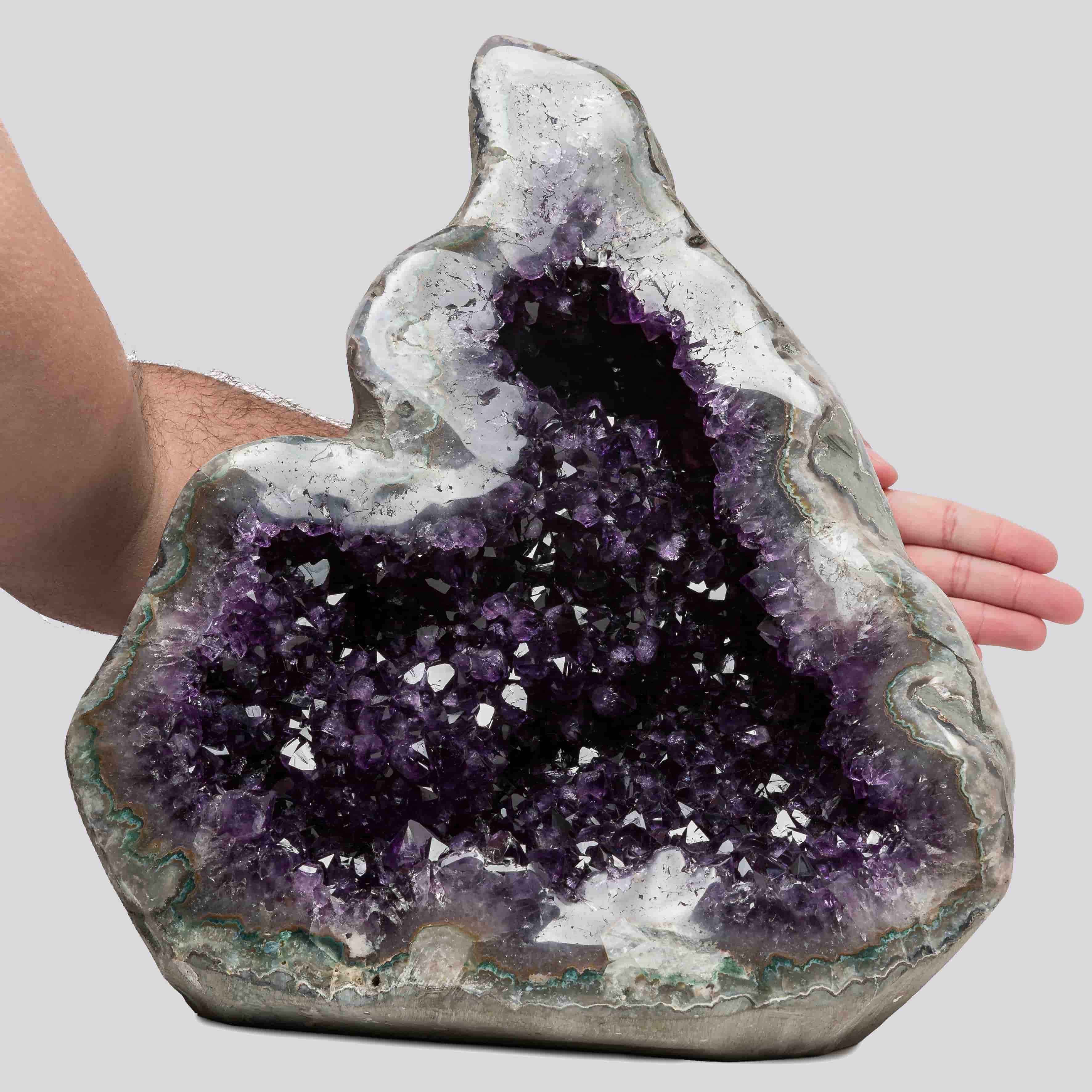 Rich amethyst geode from Uruguay featuring a deep sparkling chamber and swirling quartz textures along the outer shell.