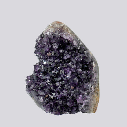 Upright Uruguayan amethyst geode with rich violet crystals and a smooth, rounded quartz-matrix top